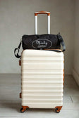 Minky Couture brand blanket duffle bag sitting on top of a cream colored suitcase.
