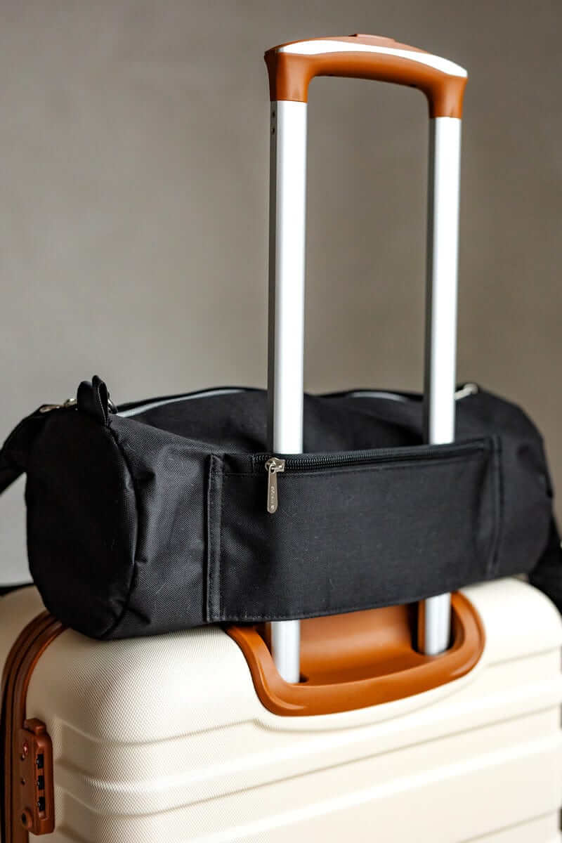 Minky Couture blanket travel bag slung over the handle of cream luggage.