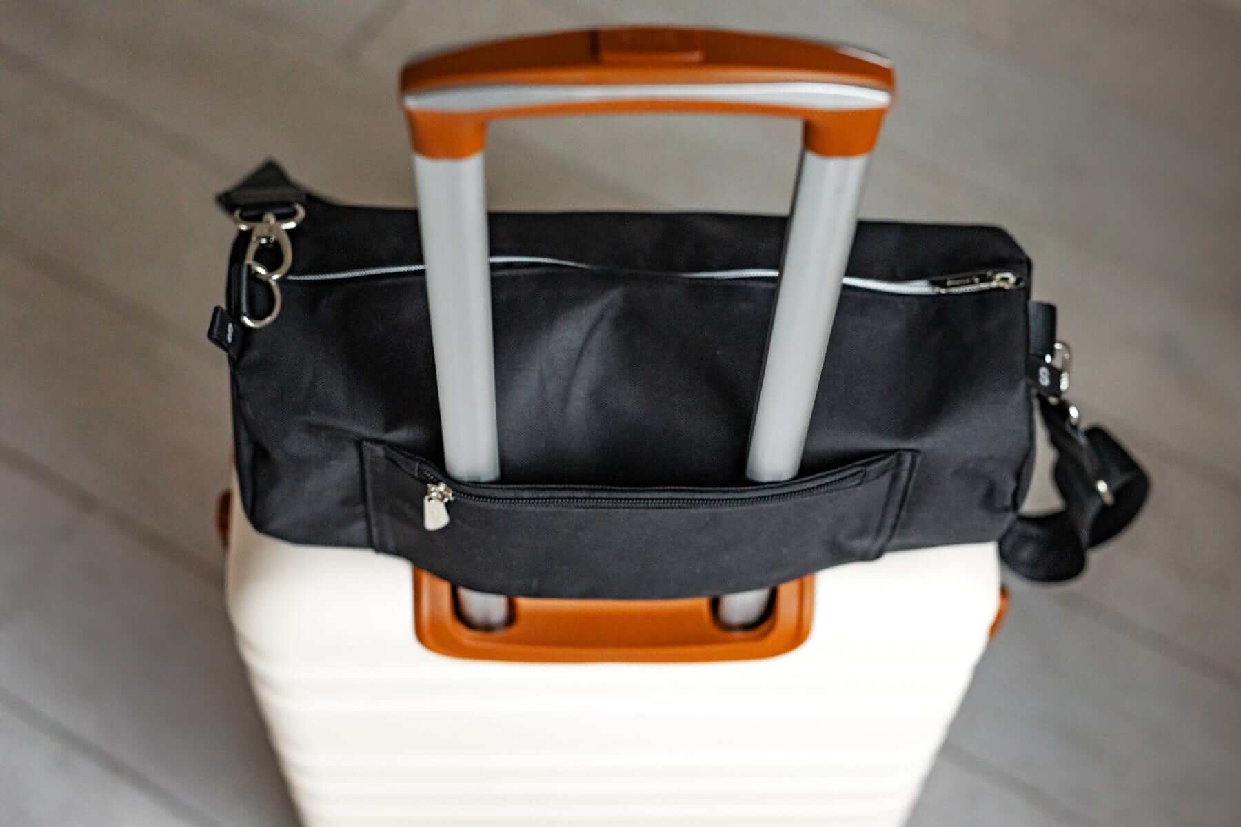 Black Minky Couture blanket travel bag fitted over the handle of a rolling suitcase.