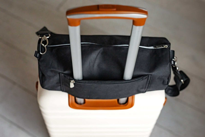Black Minky Couture blanket travel bag fitted over the handle of a rolling suitcase.