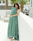 Woman wrapped in a green blanket on a patio with palm trees in the background.