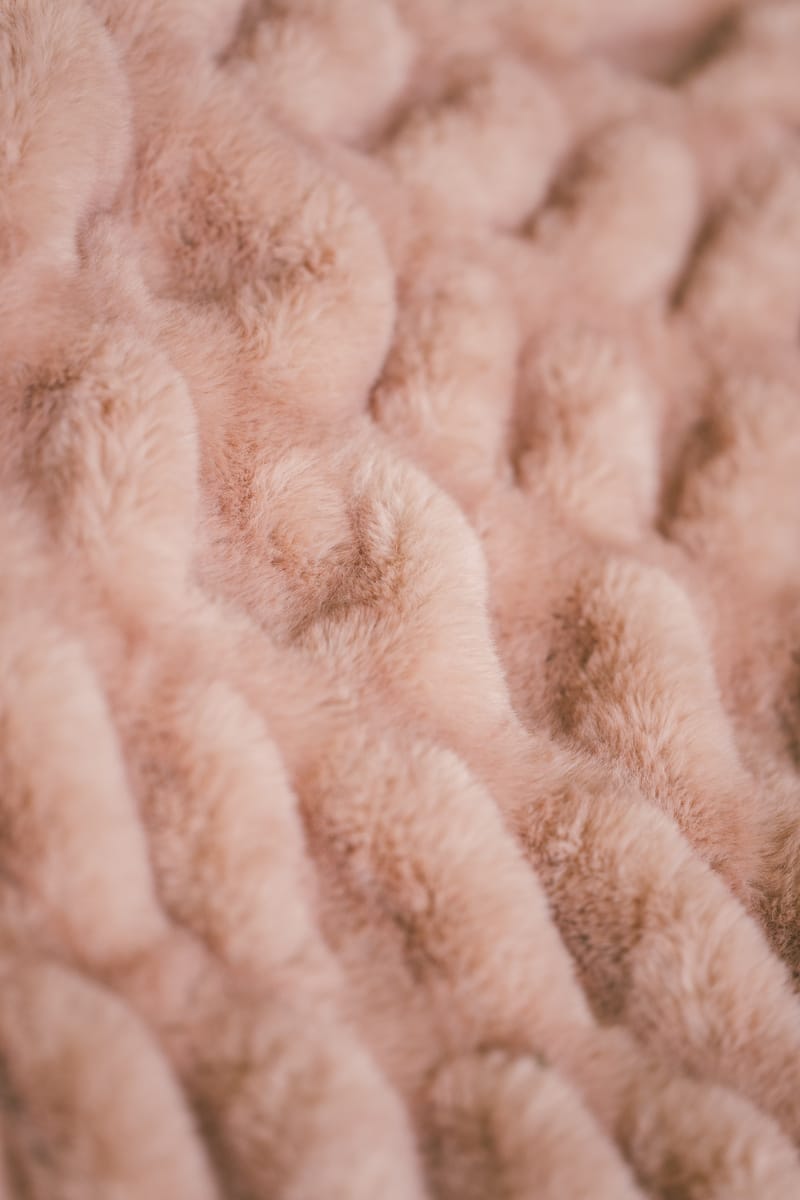 Close-up of textured pink fabric with stretchy pattern of the Hugs Blossom Blanket.