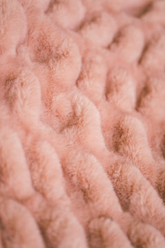 Close-up of textured pink fabric with stretchy pattern of the Hugs Blossom Blanket.