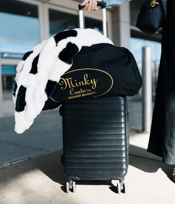 Travel Bag with a Minky blanket on top of a suitcase ready for travel at an airport.