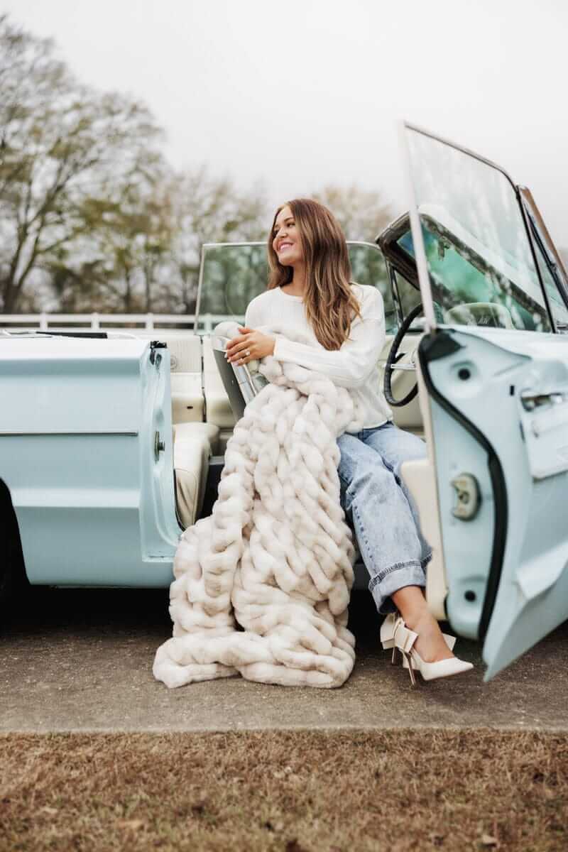 Woman sitting in a vintage convertible, wrapped in a Hugs Sophia Cream Gingham blanket.