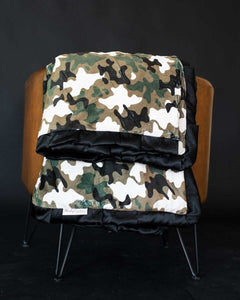 Camo Blanket folded on a chair showcasing its stylish design and plush black backing.