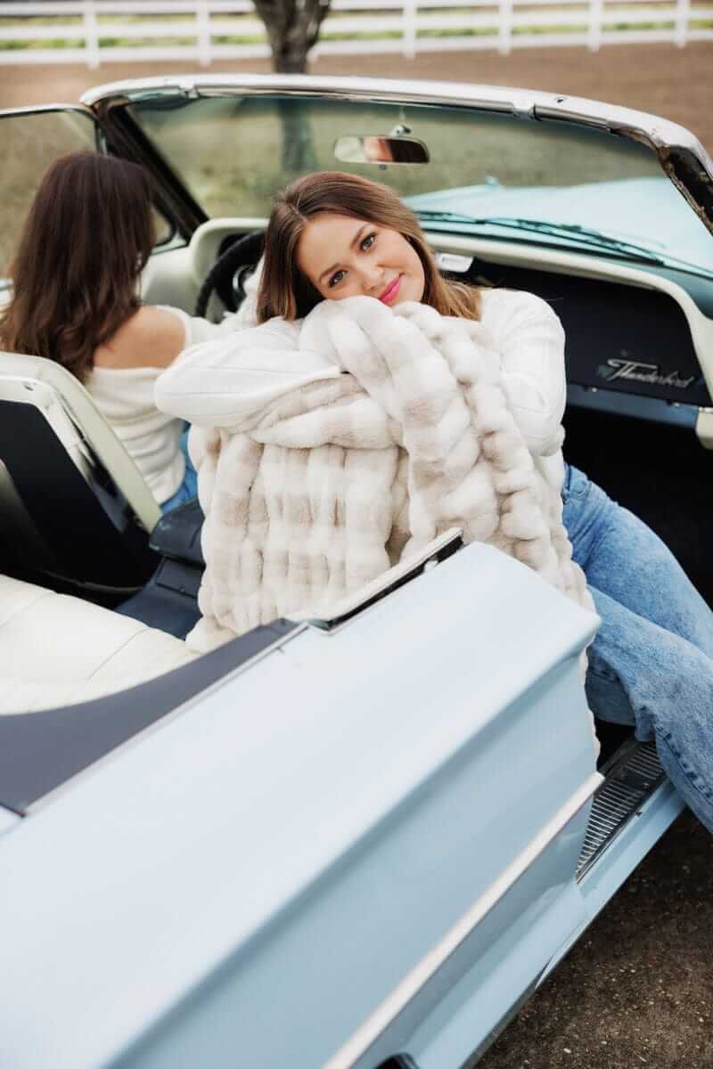 Hugs Sophia Cream Gingham Blanket styled in a cozy convertible setting with a woman embracing the plush design.