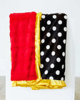 Happiest Blanket with white polka dots on a black background and plush red backing, featuring a golden yellow satin ruffle.