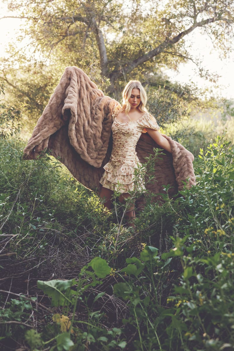 Woman in a floral dress holding the Hugs Milk Chocolate Blanket in a lush outdoor setting.
