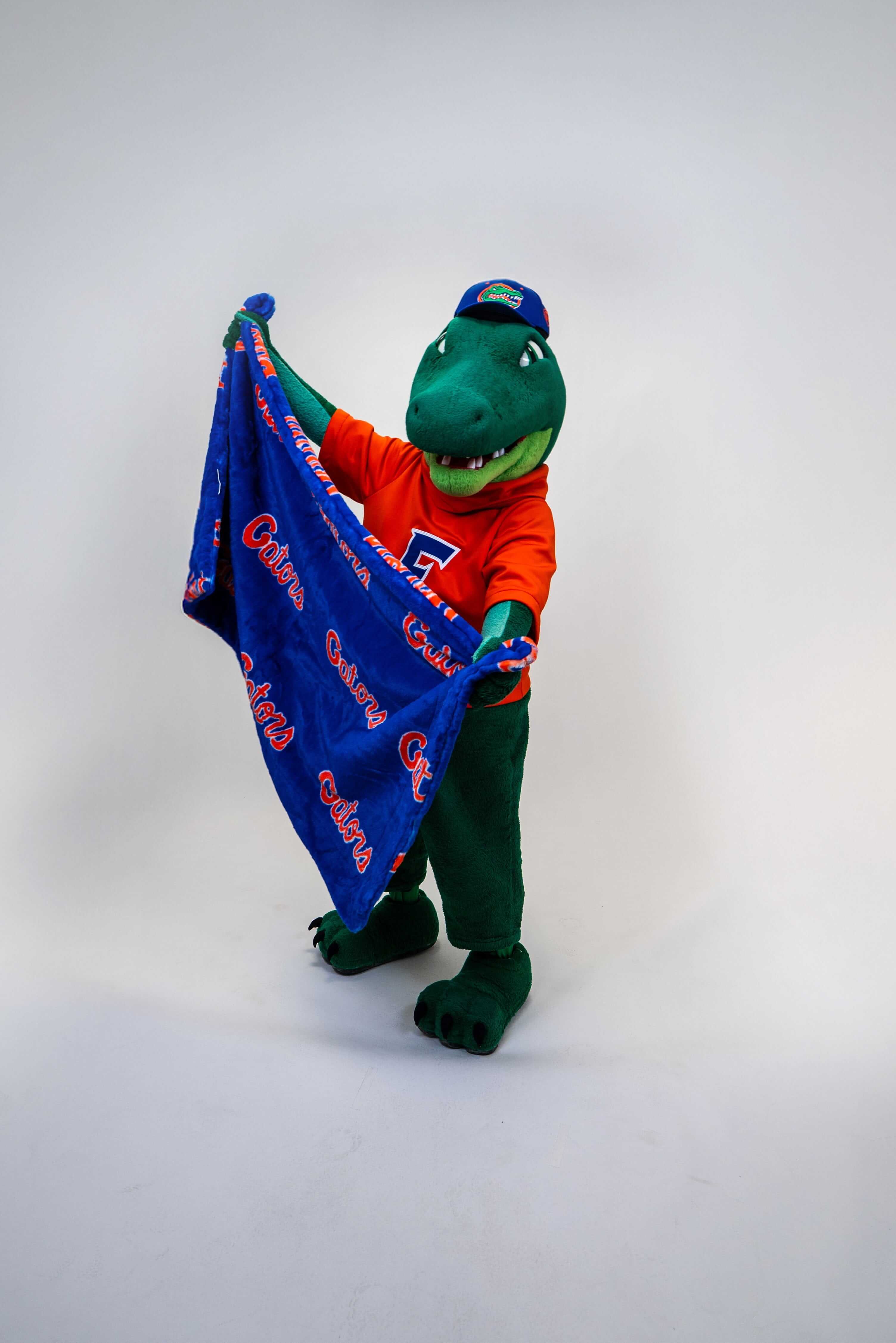 Lush Florida Gators Blanket displayed by mascot holding a blue blanket with orange Gators logo.