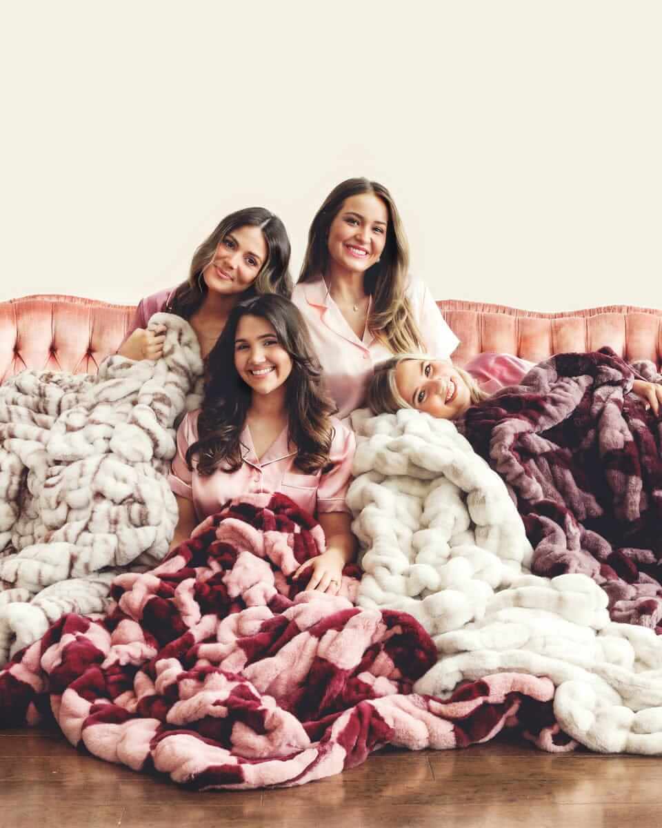 Four women smiling together, wrapped in plush Minky Couture blankets.