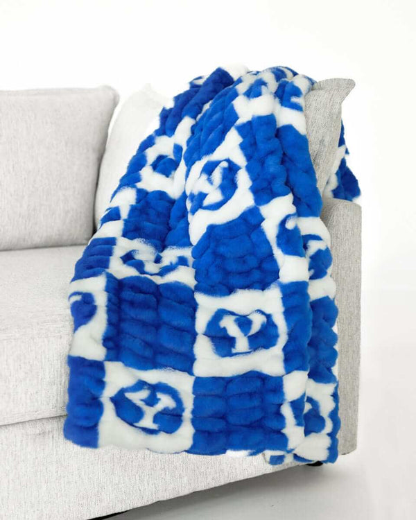 Minky Couture BYU Cougars Blanket draped over a couch, featuring a blue and white checkered design with the BYU logo.