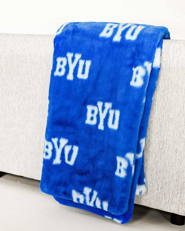 BYU Cougars Blanket displayed on a sofa, showcasing its blue ultra-plush fabric and BYU logo design.