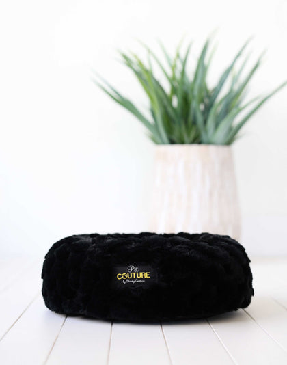 Black Crinkle Pet Bed cover displayed on a light floor, surrounded by greenery in the background.