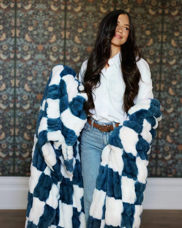 Woman wearing Hugs Check Blue Blanket, showcasing its plush checkered pattern in white and deep navy.