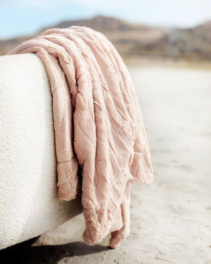 Sorbet Blush Pink Blanket gently resting on a cozy couch, showcasing its soft texture and charming blush color.
