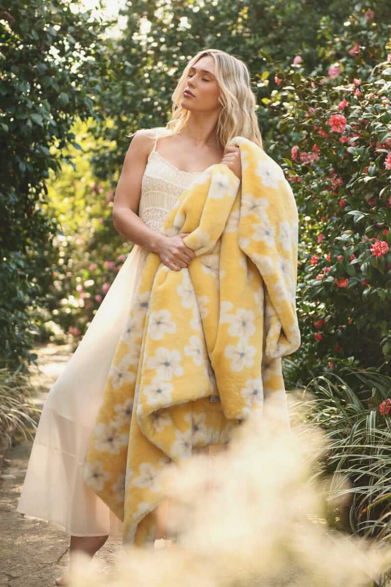 Lush Butter Yellow Floral Blanket draped over a model in a floral garden, showcasing its vibrant yellow hue and floral design.