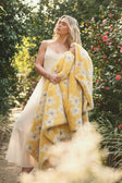 Lush Butter Yellow Floral Blanket draped over a model in a floral garden, showcasing its vibrant yellow hue and floral design.