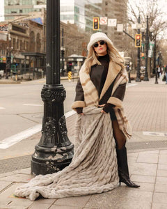 Woman in stylish coat showcasing the Biggest Hugs Tranquil Dove weighted Blanket in a city street.