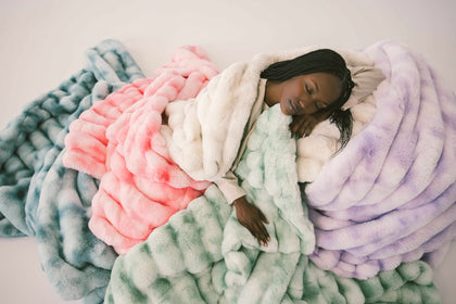 Woman relaxing on colorful plush Minky Couture Extreme Ultra Cloud weighted blankets for ultimate comfort.