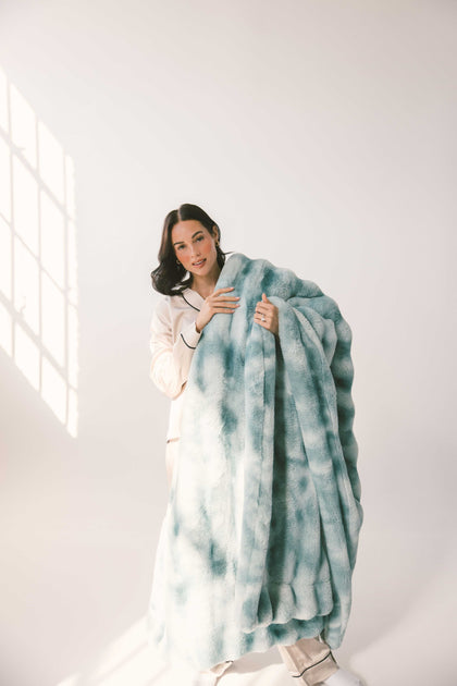 A woman holding the Extreme Ultra Cloud Smoke Blue weighted blanket, showcasing its plush texture and rich blue hue.