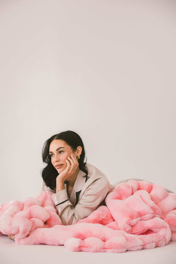 Model relaxing with the Extreme Ultra Cloud Pink Lemonade weighted Blanket, showcasing its vibrant pink color and plush texture.