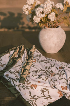 Vase with white flowers on a table with peony patterned blanket.