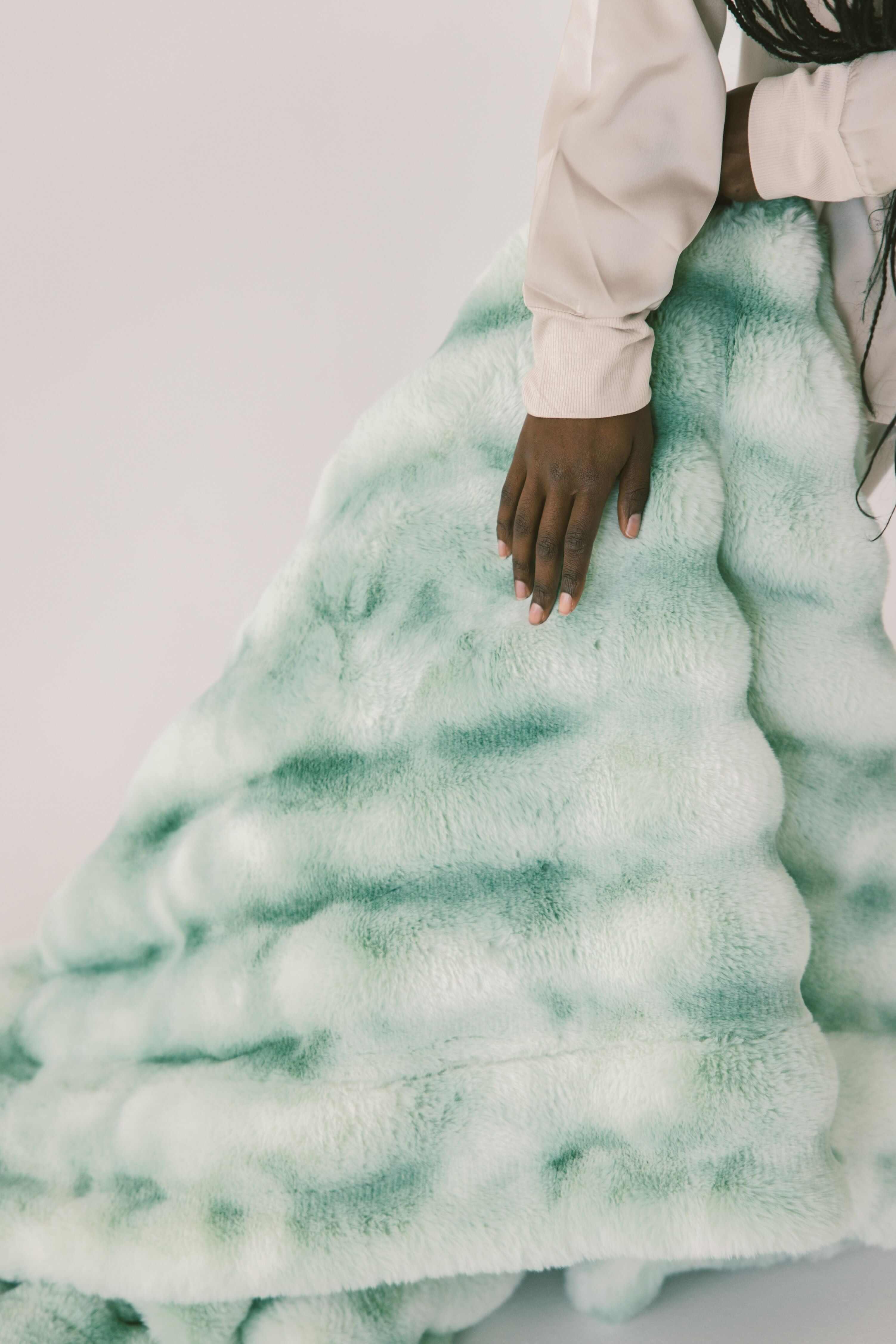 Extreme Ultra Cloud Malachite Green Blanket displayed with a hand, showcasing its plush texture and rich green hues.