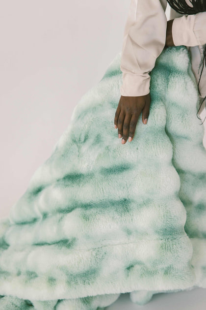 Extreme Ultra Cloud Malachite Green Blanket displayed with a hand, showcasing its plush texture and rich green hues.
