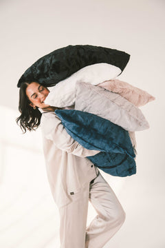 Woman holding multiple colorful Sorbet Pillowcases - Standard Size, showcasing soft bedding in various shades.