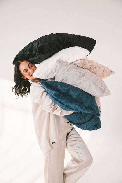 Woman holding multiple colorful Sorbet Pillowcases - Standard Size, showcasing soft bedding in various shades.