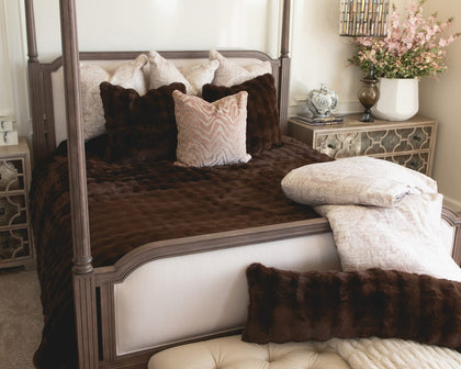 Decorative bedroom with a four-poster bed, brown and white bedding, and a nightstand with a lamp.