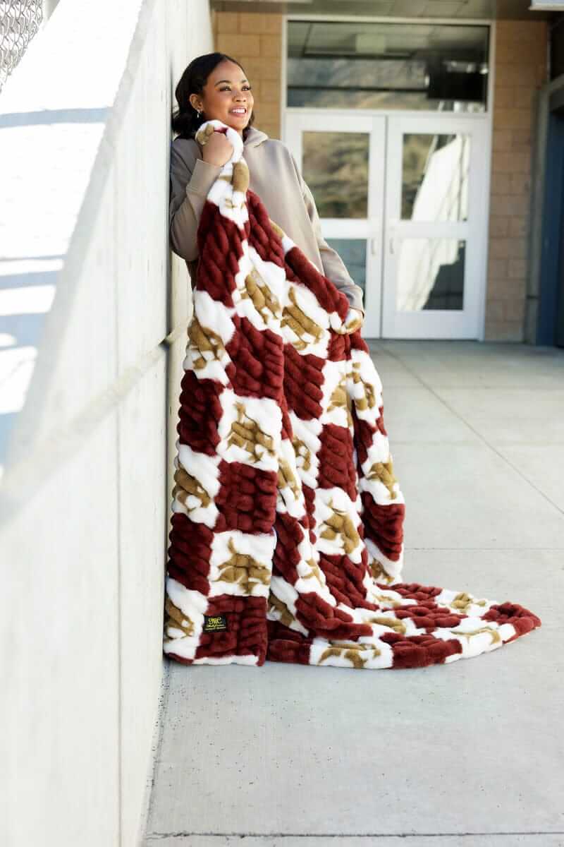 Hugs Texas State Bobcats Blanket displayed by a woman wrapped in a plush, maroon and white checkered blanket.
