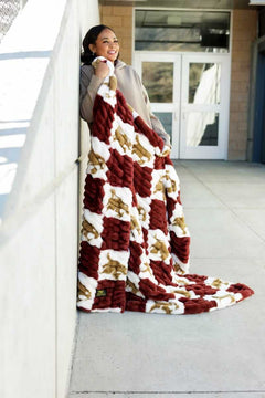 Hugs Texas State Bobcats Blanket displayed by a woman wrapped in a plush, maroon and white checkered blanket.