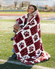 A person wrapped in a cozy Mississippi State Bulldogs Blanket featuring a maroon and white checkered pattern.