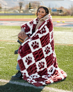 A person wrapped in a cozy Mississippi State Bulldogs Blanket featuring a maroon and white checkered pattern.
