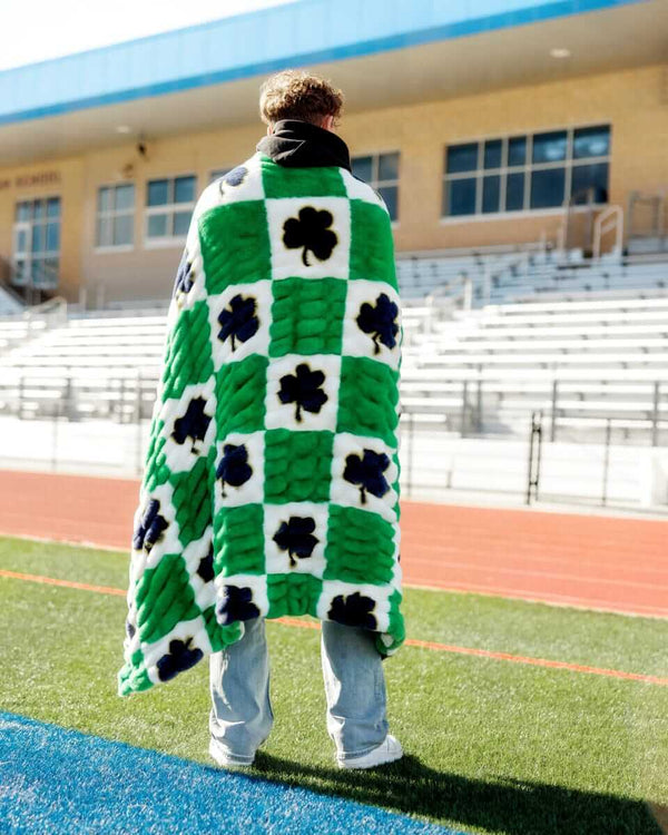 Notre Dame Fighting Irish Blanket draped over a person on a football field showcasing its green and white checkered pattern.