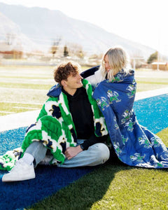 Notre Dame Fighting Irish Hooded Stadium Blanket used by a couple outdoors on a sunny day.