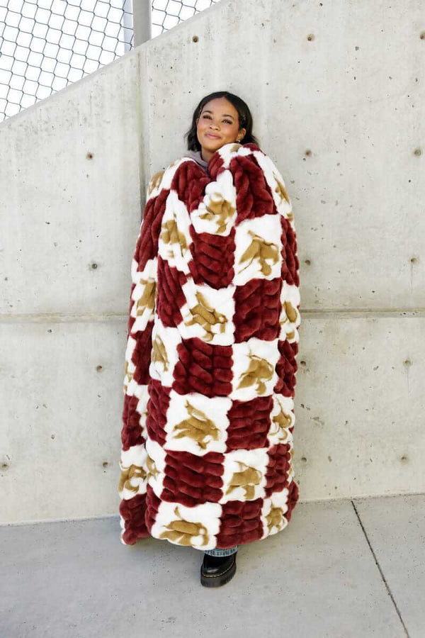Texas State Bobcats Blanket draped over a person, featuring a maroon and white checkered pattern with a gold logo.