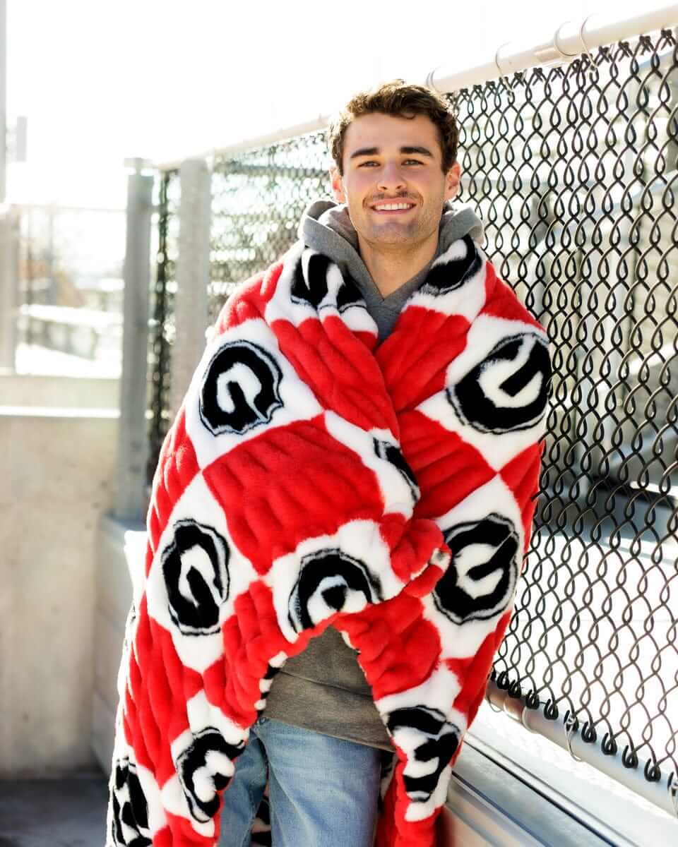 Georgia Bulldogs Blanket wrapped around a smiling man outdoors, featuring a bold red and white checkered pattern.