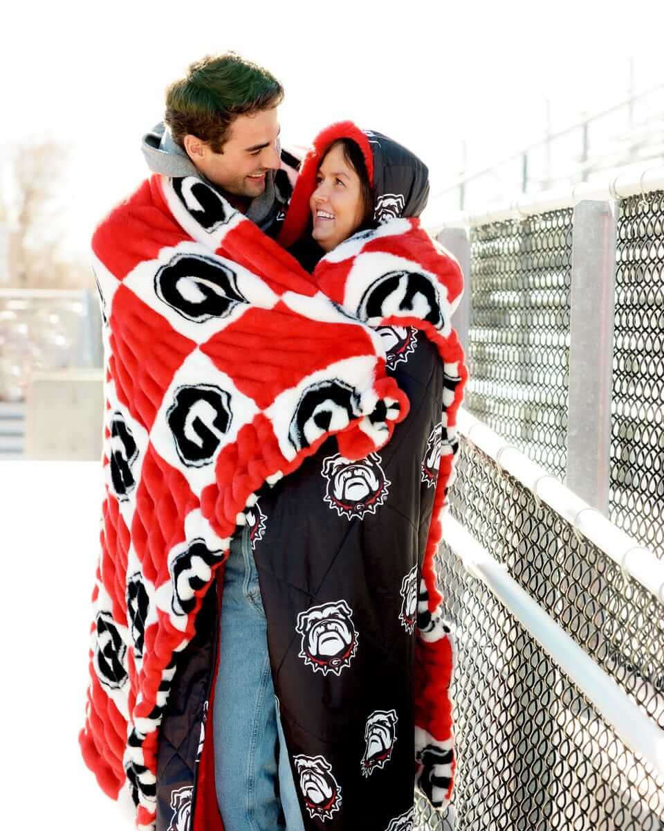 Hugs Georgia Bulldogs Blanket used by a couple, showcasing team spirit and cozy comfort on a chilly day.