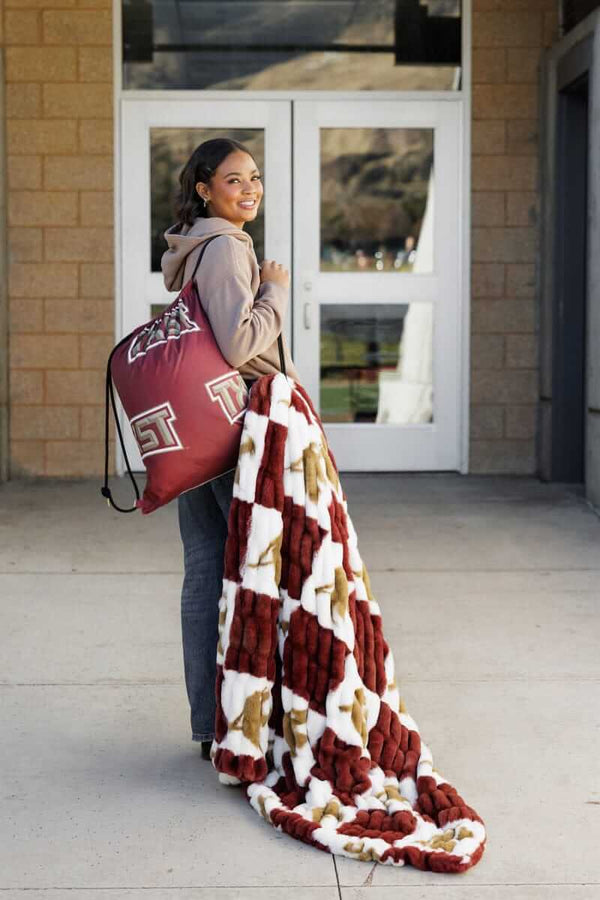 Texas State Bobcats Hooded Stadium Blanket displayed by a woman outside, showcasing Bobcat pride and style.