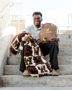 Wyoming Cowboys Hooded Stadium Blanket, shown on a person sitting on stairs, highlighting warmth and comfort.