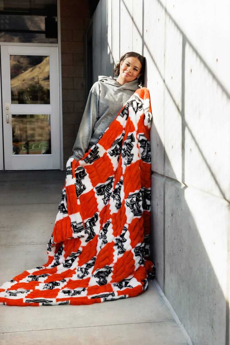 Texas Tech Raiders Blanket displayed by a young woman, showcasing its vibrant red and white checkered design.