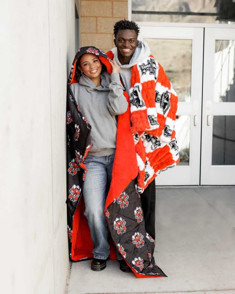 Texas Tech Raiders Hooded Stadium Blanket being worn by two people standing by a wall.