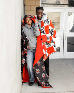 Texas Tech Raiders Hooded Stadium Blanket being worn by two people standing by a wall.