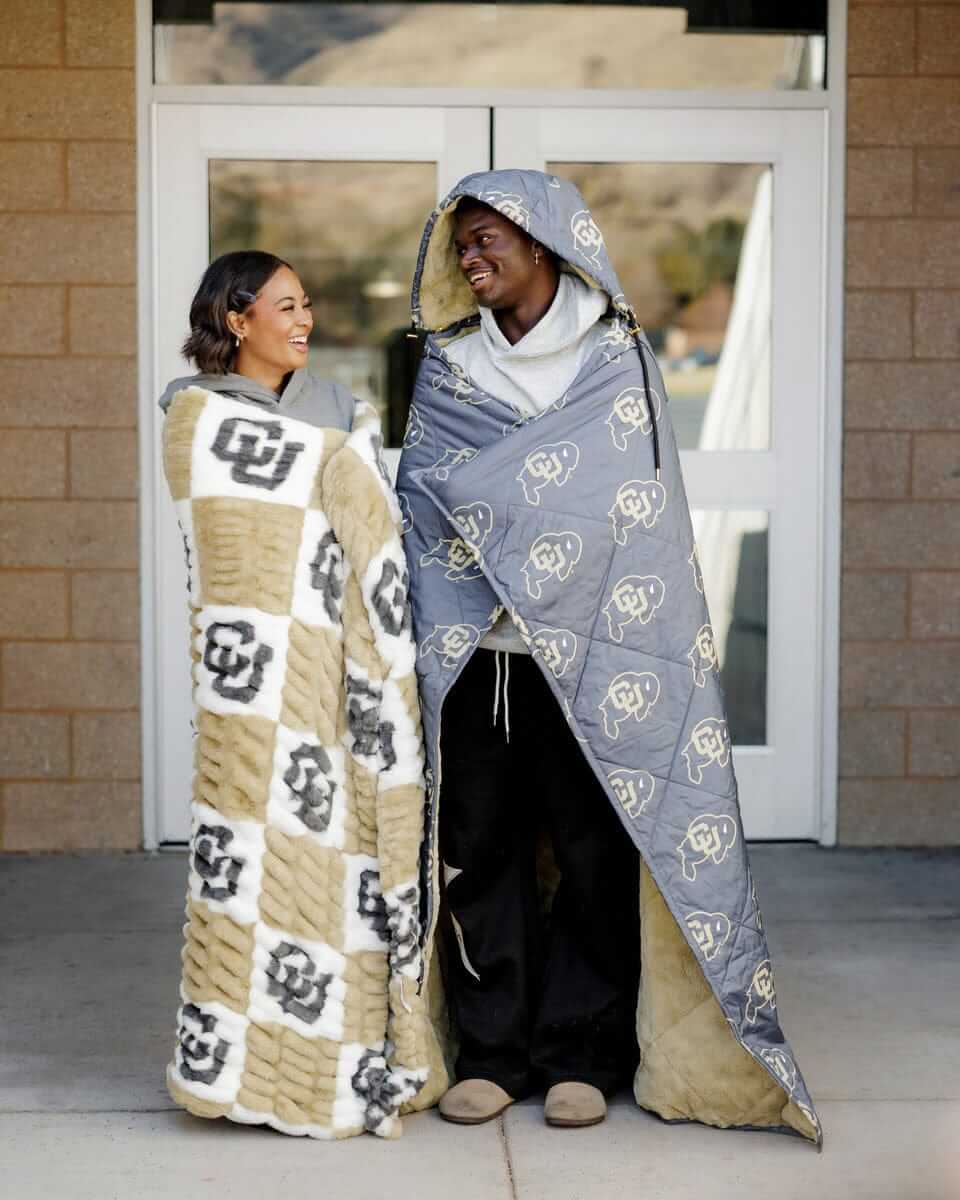 Hugs Colorado Buffaloes Blanket Cozy couple wearing CU themed blankets, showcasing team pride and comfort.