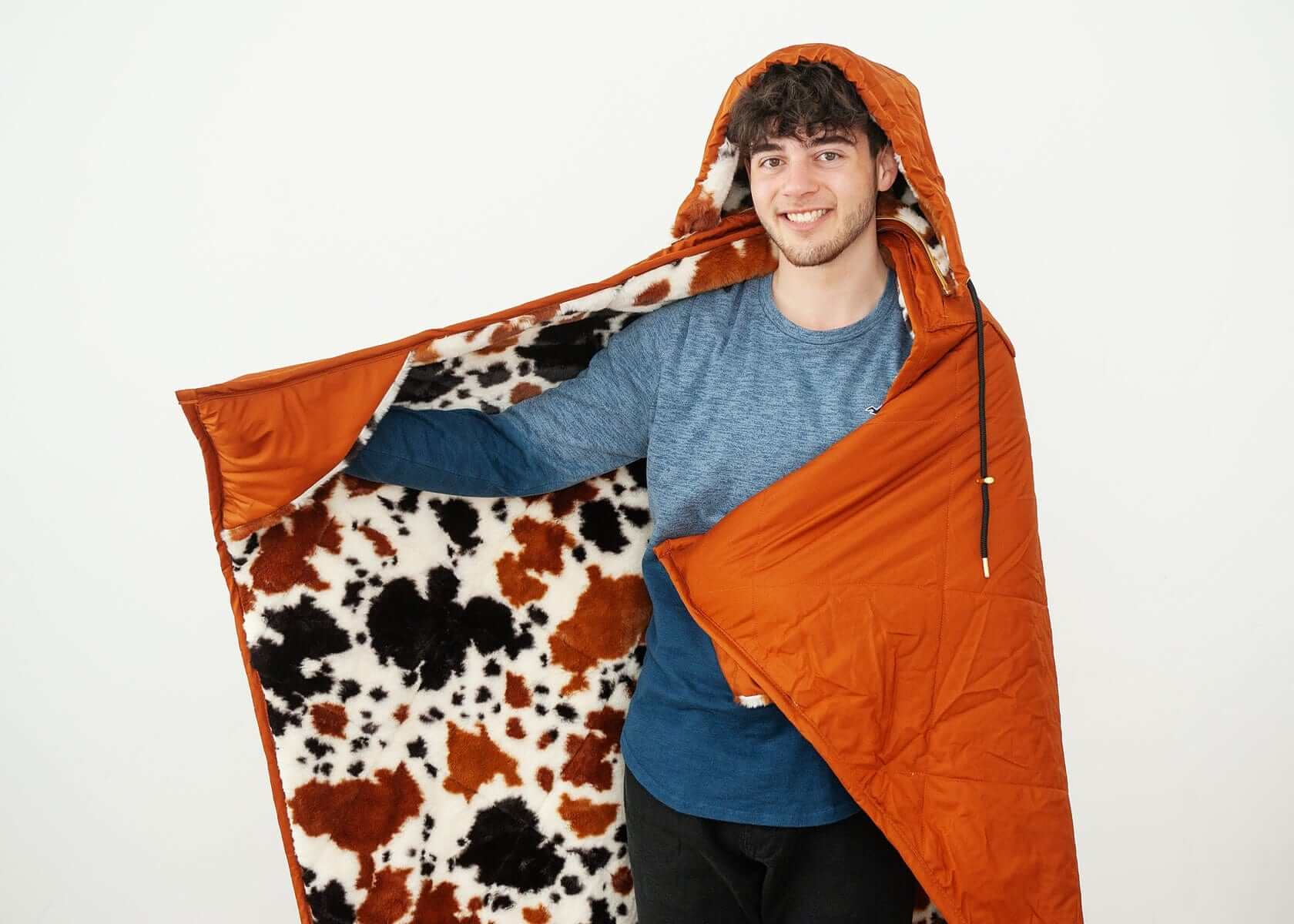 Person enjoying the Everywhere Blanket Brown Cow with its cozy cow print interior and vibrant camel brown exterior.