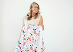 Woman smiling while holding the Baby Bloom Blanket with floral pattern, perfect for cozy moments.
