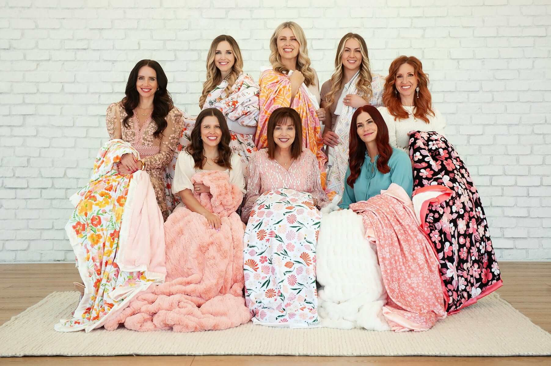 A group of women showcasing various colorful Baby Bloom Blankets in a cozy setting.